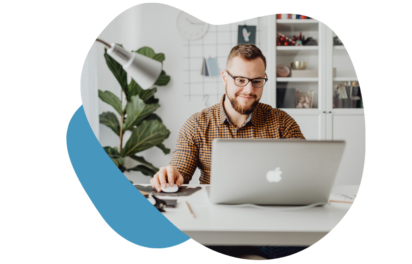 Mann mit Brille und Karohemd sitzt am Schreibtisch am Laptop