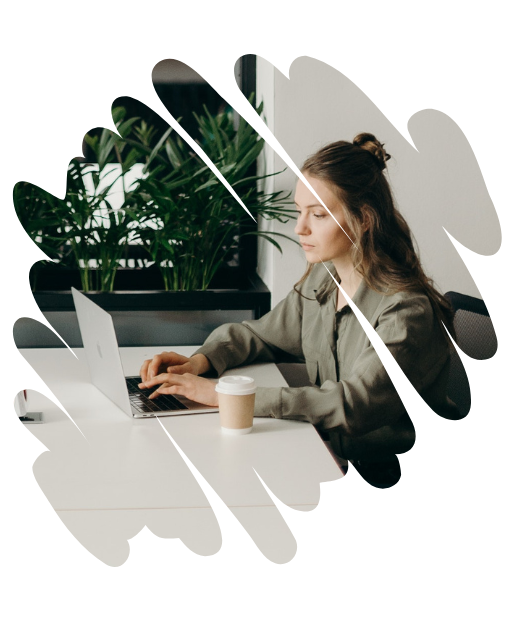 Frau sitzt am Tisch und arbeitet am Laptop 